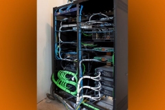 Back of an equipment rack: blue, green and white cables bundled and tied to each component
