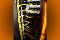 Side of an equipment rack with yellow cables dressed down the frame to each component