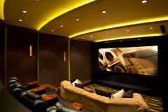 Home theater with gold cove lighting, a large screen, a curved sofa and leather recliners with side tables