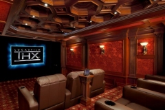THX Certified screening room with the THX logo on screen, coffered wood ceiling, red damask walls and leather recliners