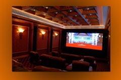 Home theater with red patterned wall panels, sconces, a lit coffered ceiling and leather recliners