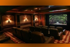 Home theater with three rows of leather recliners, red checkered carpet, sconces and a lit coffered ceiling