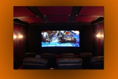 Home theater with a red fabric ceiling between dark beams, red wall panels and leather recliners facing the screen