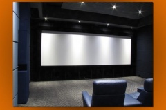Modern home theater with a wide screen, gray fabric walls, slatted ceiling and blue leather recliners