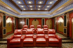Home theater with two tiered rows of red leather recliners, a lattice-painted ceiling cove and arched wall niches with sconces