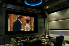Starship bridge themed home theater with console desks, gray paneled walls and a domed star ceiling light