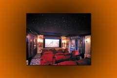 Italian village themed home theater with a star ceiling, painted shopfronts and rows of red recliners