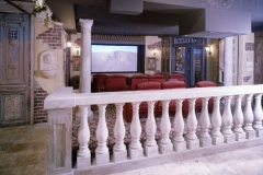 Italian village themed home theater seen over a stone balustrade, with red seats facing the screen