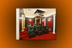 Home theater with a projector on a ceiling lift, white columns, red wall panels and black leather recliners