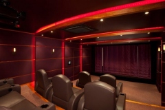 Home theater with red LED strip lighting along the ceiling soffits, padded wall panels and leather recliners