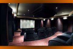 Home theater with curved rows of dark fabric recliners on tiered platforms facing a white screen