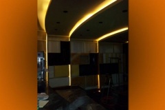Theater under construction with curved lit ceiling soffits and unfinished wall panels
