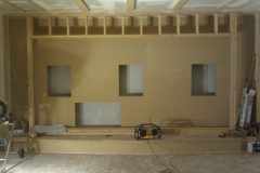 Screen wall framed in wood with three openings for front speakers above a built-up stage
