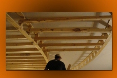 Worker beneath curved wood framing for a theater ceiling soffit
