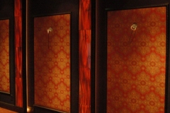 Patterned red fabric wall panels between red wood-grain pilasters