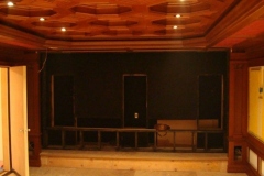 Theater with an octagonal coffered wood ceiling, front wall framed for speakers and a stage riser