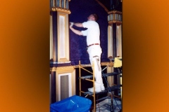 Worker on scaffolding fitting fabric wall panels between gilded columns