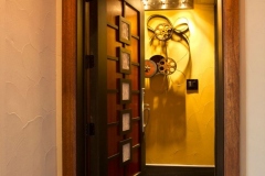 Theater door with framed photos, opening onto a gold wall hung with vintage film reels