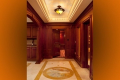 Theater entrance foyer with marble floor and inlaid medallion, wood paneling and the door open to the screening room