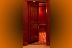 Paneled wood door opening into a red theater