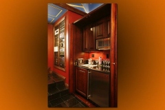 Theater kitchenette with wood cabinets, sink, beverage fridge and microwave beside the theater steps