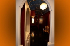Arched doorway into a lobby with a starry painted ceiling, crystal chandelier and black polished floor
