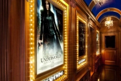 Marquee-lit movie poster frame in a wood-paneled corridor with a vaulted blue ceiling