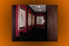 Hallway to the theater lined with framed portrait drawings on red walls