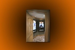 Carved wood door open to a lobby with lit movie poster cases