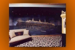 Theater lounge with a painted mural of an ocean liner at night and a cushioned settee