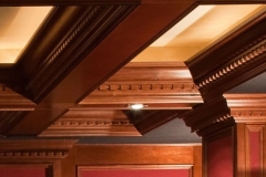 Coffered ceiling beams with dentil molding above carved wood pilasters