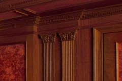 Pair of fluted wood pilasters with carved capitals between red faux-finish wall panels