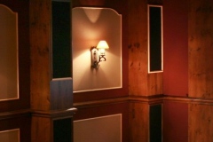 Knotty wood wall paneling with inset panels, a sconce and tall dark inset strips
