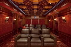 Rear of the screening room: raised back row of four recliners, lit steps and the projector port above