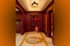 Theater entrance foyer with marble floor and inlaid medallion, wood paneling and the door open to the screening room