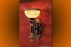 Bronze wall sconce with marbled glass shade on a red damask wall panel