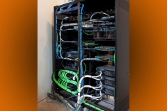 Back of the equipment rack: blue, green and white cables bundled and tied to each component